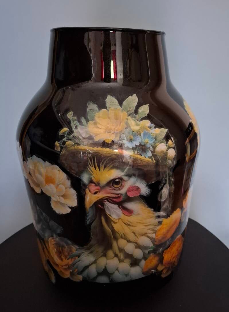 Zwarte vaas met reverse decouopage met een afbeelding van een aangeklede kip en bloemen