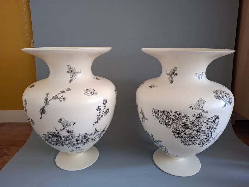 Twee grote roomwitte bewerkte vazen met zwarte bloemen, vogels en vlinders als verfijnde decoratie
