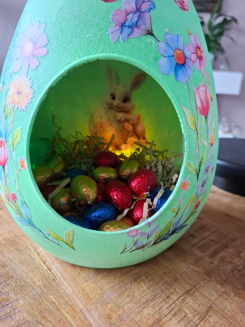 Handbewerkt glazen ei met opening aan de voorkant, versierd met voorjaarsbloemen, lammetjes en haasjes als sfeervolle paasdecoratie