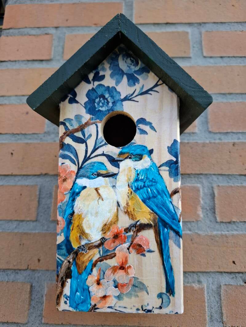 Handbeschilderd vogelhuisje met blauwe bloemen en vogels op een kersenbloesemtak