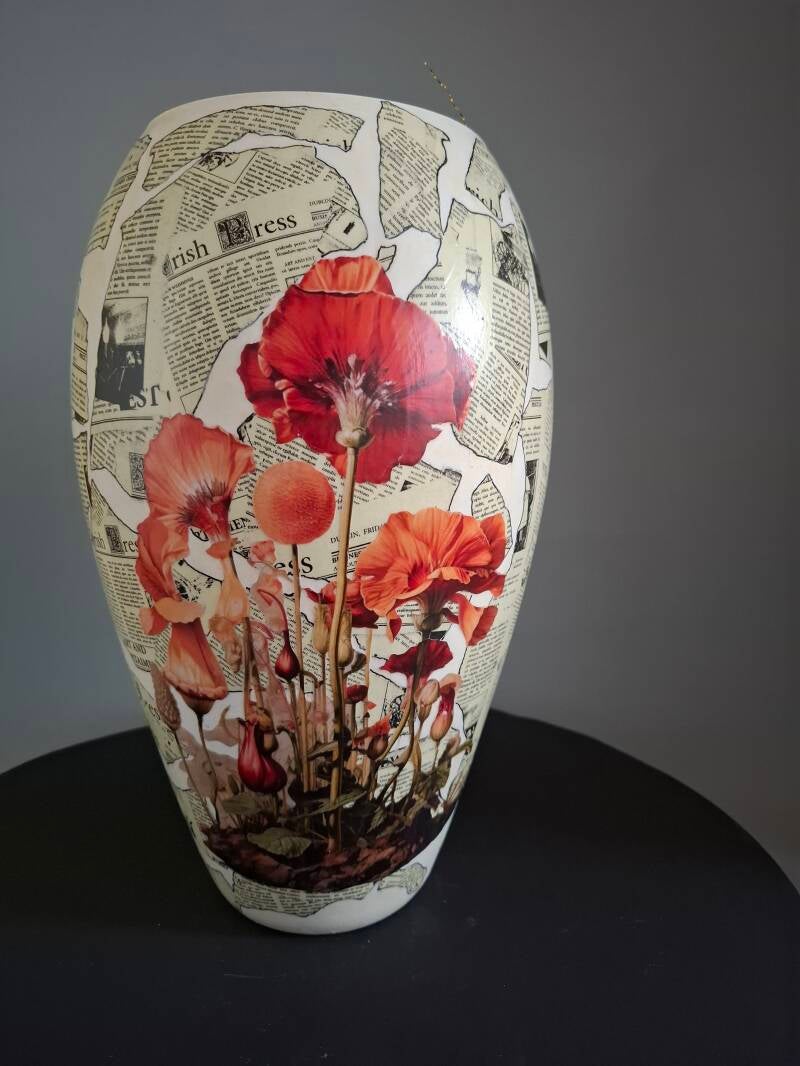 Glazen vaas met krantenknipsels en rode bloemen