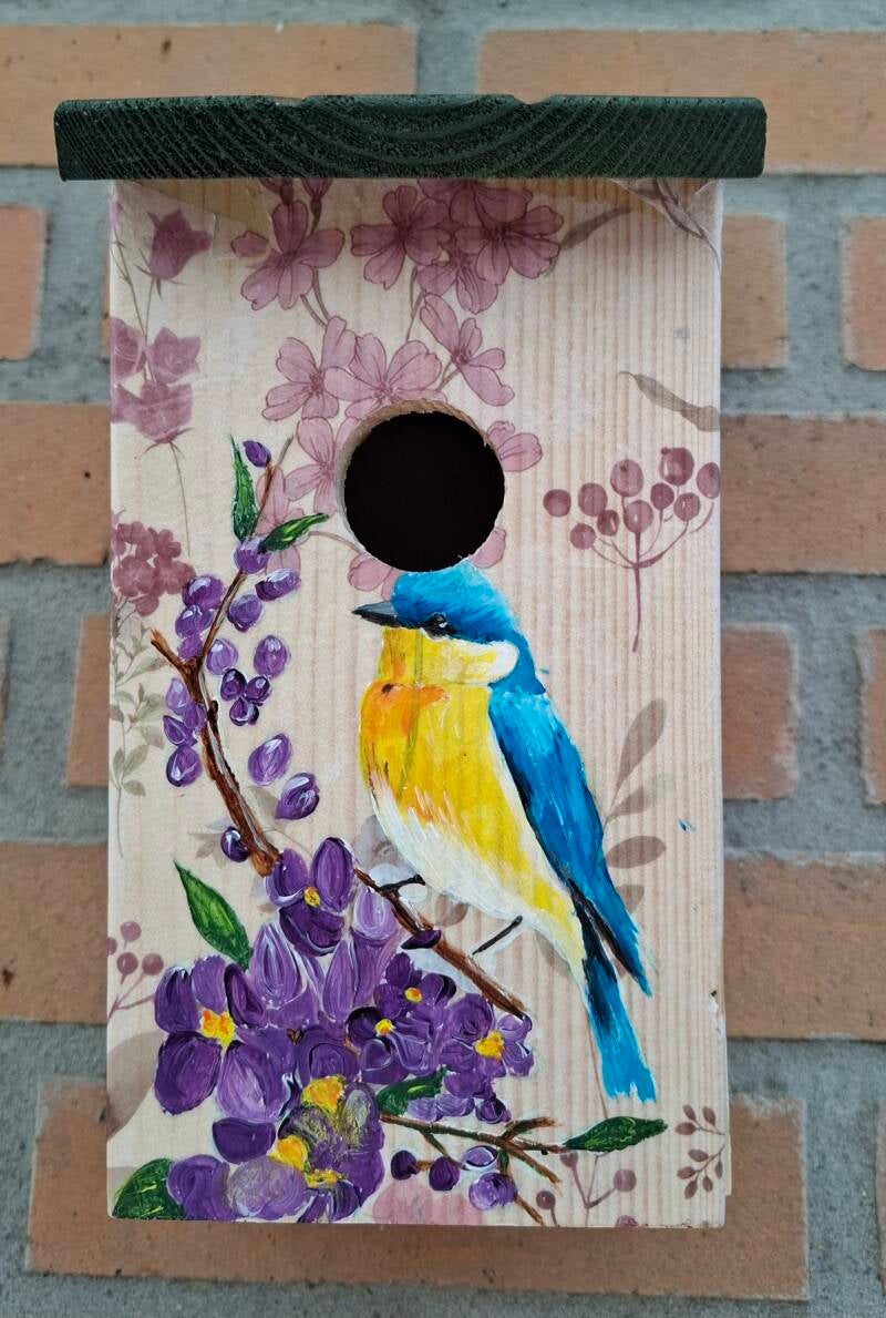 Houten vogelhuisje met beschilderd vogletjenop een paarse bloementak
