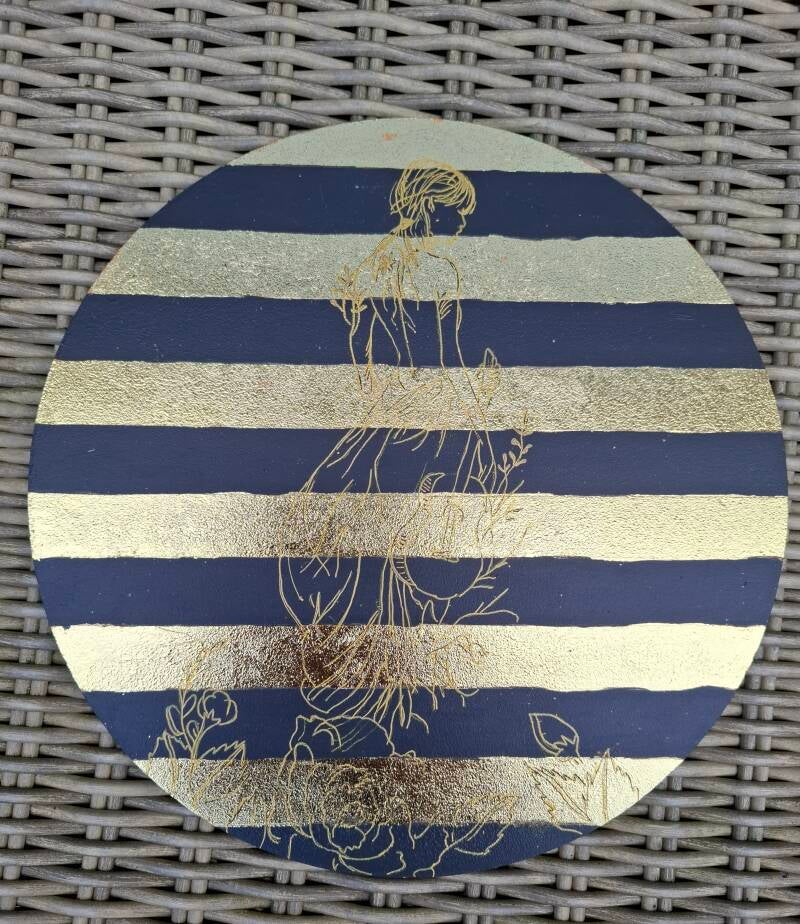Handgemaakte muurcirkel van 30 cm met donkerblauwe strepen, metallic goudfolie en een verfijnd vrouwensilhouet in goud