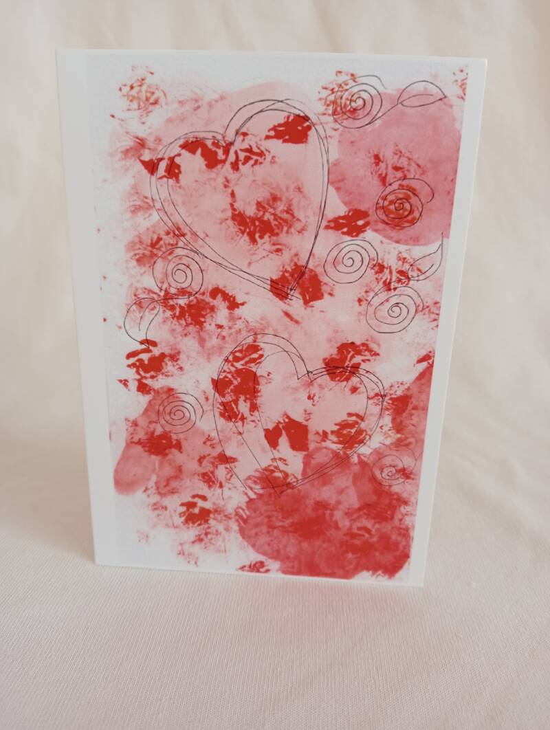 dubbele kaart met een rode gevlekte achtergrond met daarin hartjes.  inclusief envelop