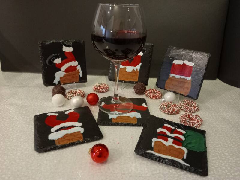 Zes handbeschilderde leistenen kerstonderzetters met grappige kerstmannen in een schoorsteen.