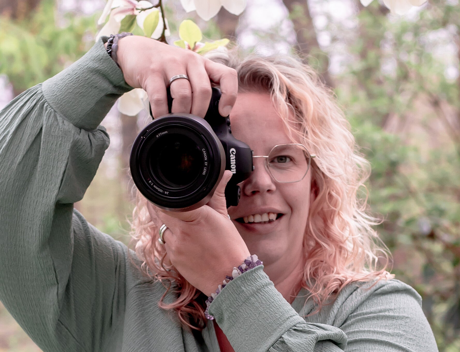 Eigenaar die tijdens haar eigen boudoirshoot op de grond zit met de rug tegen het bed voor een mooie foto