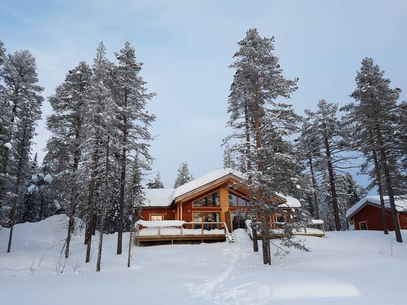 Row of houses covered in a thick layer of snow, with snow-capped roofs and wintery surroundings.