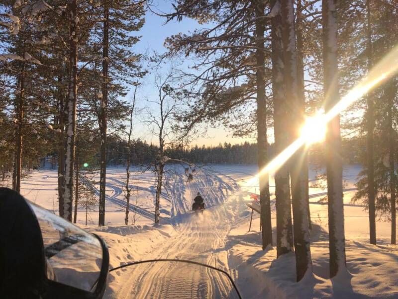 Snowmobiles riding through pristine white landscape in Swedish Lapland.