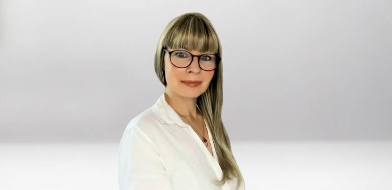 Jana Lorenz mit langen blonden Haaren, trägt weiße Bluse und goldene Ohrringe, Halskette mit rundem roten Anhänger, Kontext Mediumship  & Research Institut für Medialität & Afterlife Forschung