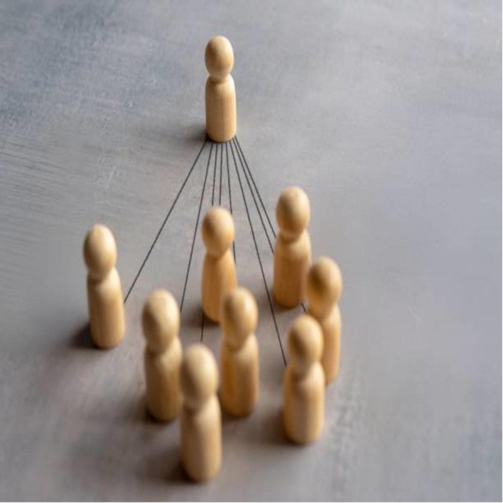Acht stilisierte, blaue Papiersilhouetten von Menschen, die sich an den Händen halten, auf einer glatten Oberfläche, Blog MediumSciences - Institut