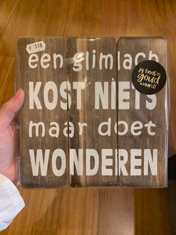 vierkant houten bordje "een glimlach kost niets maar..."