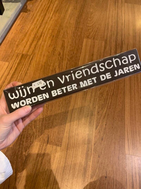Houten bordje staand "wijn en vriendschap worden...."