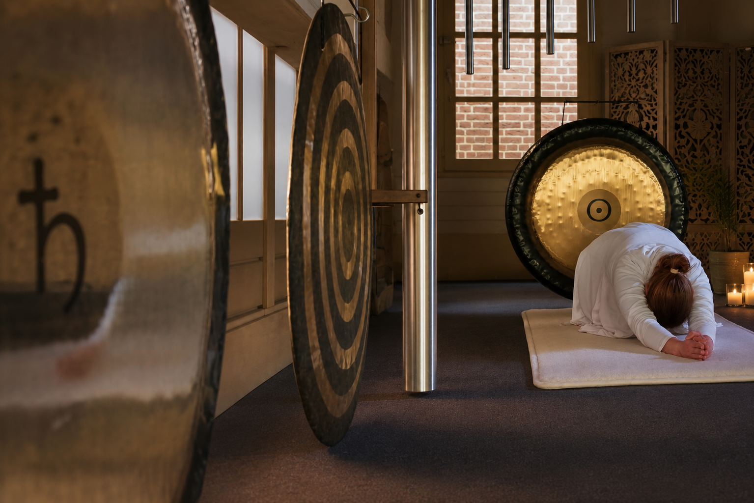 Docent beoefent Kundalini Yoga in Child's Pose tussen gongs en kristallen klankschalen in de yogastudio van Kundalini Yoga Sat Nam in Lith, nabij Oss.