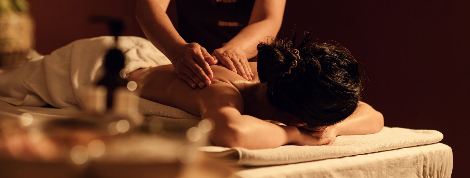 Femme allongée sur une table dans un espace bien-être, en train de recevoir un massage dans une ambiance chaleureuse