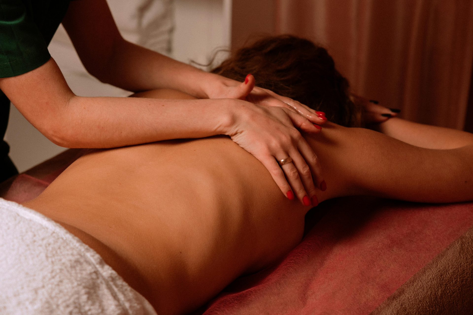 Femme allongée sur une table dans un espace bien-être, en train de recevoir un massage dans une ambiance chaleureuse