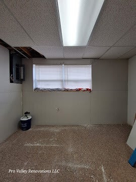 Partially renovated room with drop ceiling, drywall bucket, and exposed wiring.