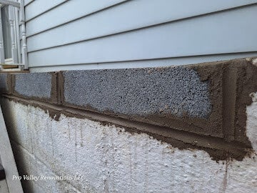Foundation wall repair showing newly installed concrete blocks and mortar.