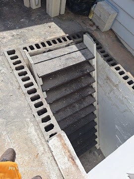 Concrete stairway leading to basement or cellar entrance with cinder block walls.