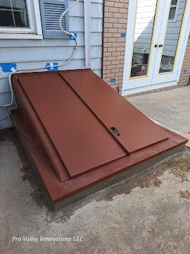 Exterior metal cellar door installed against house foundation.