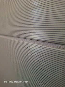 Close-up abstract pattern of modern acoustic slat wood-look paneling with deep horizontal grooves and texture.
