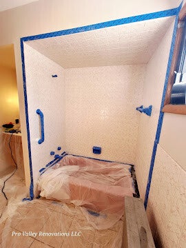 A wide view of a walk-in shower area completely prepped for contracting, covered with painter's tape and plastic sheeting by Pro Valley Renovations LLC.