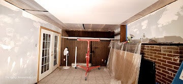 Room undergoing renovation with drywall lift holding ceiling sheet in place.