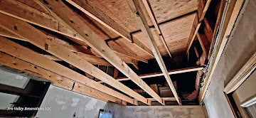 Exposed wooden ceiling beams and framing during home renovation.
