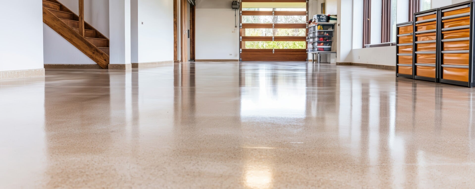 Modern garage or workshop with polished concrete floor, tool cabinets, and large windows.