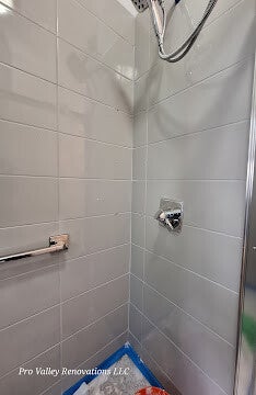 Close-up of professional shower tile installation with light grey horizontal subway tiles and chrome fixtures by Pro Valley Renovations LLC.