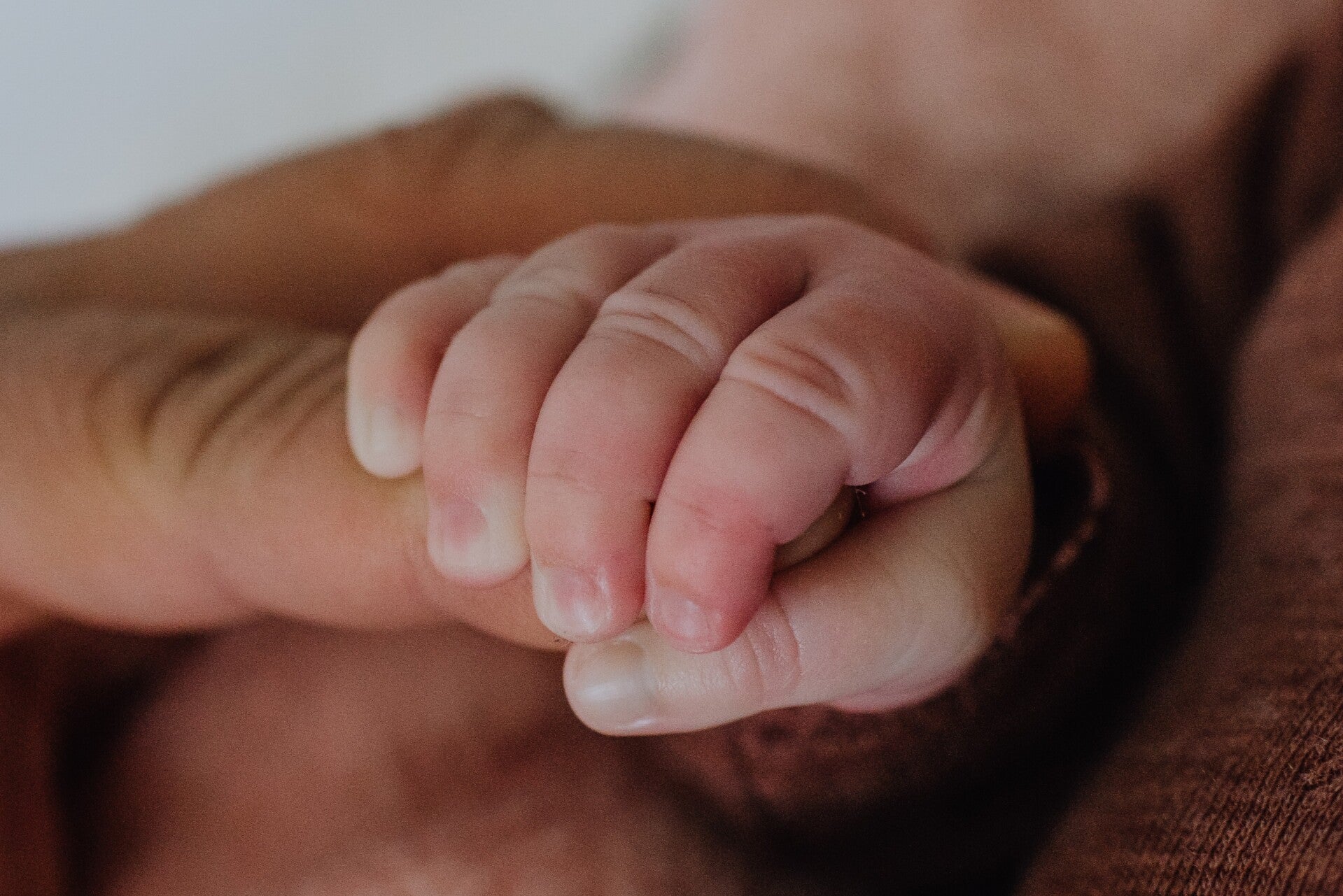 eine Babyhand hält den Finger eines Erwachsenen