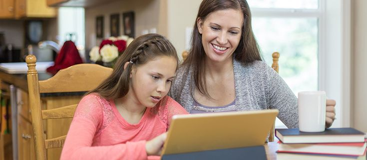 Mother and daughter smiling at a laptop during online UK entrance exam tuition.