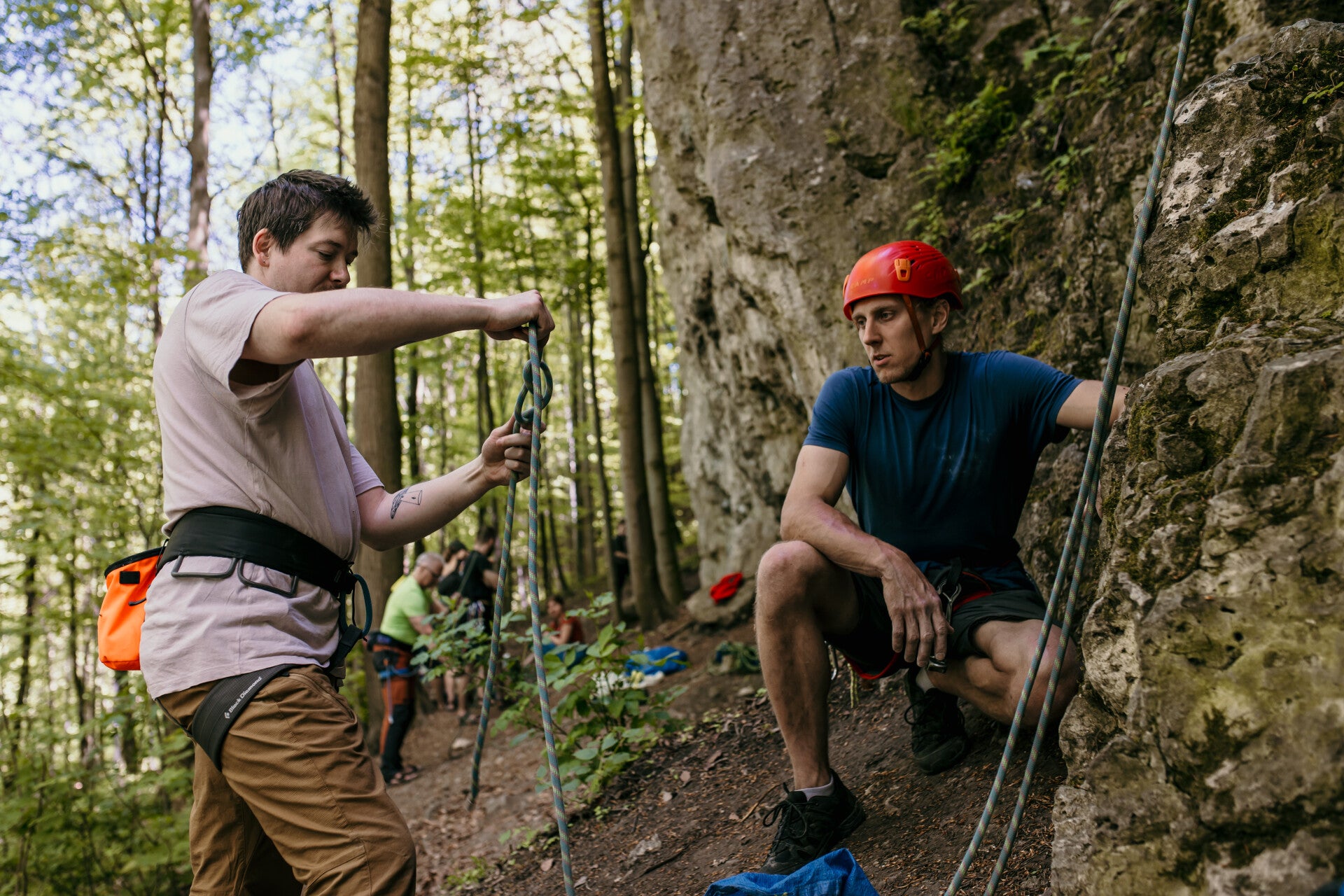 Beginner climber with an climbing instructor trying to tie a knot