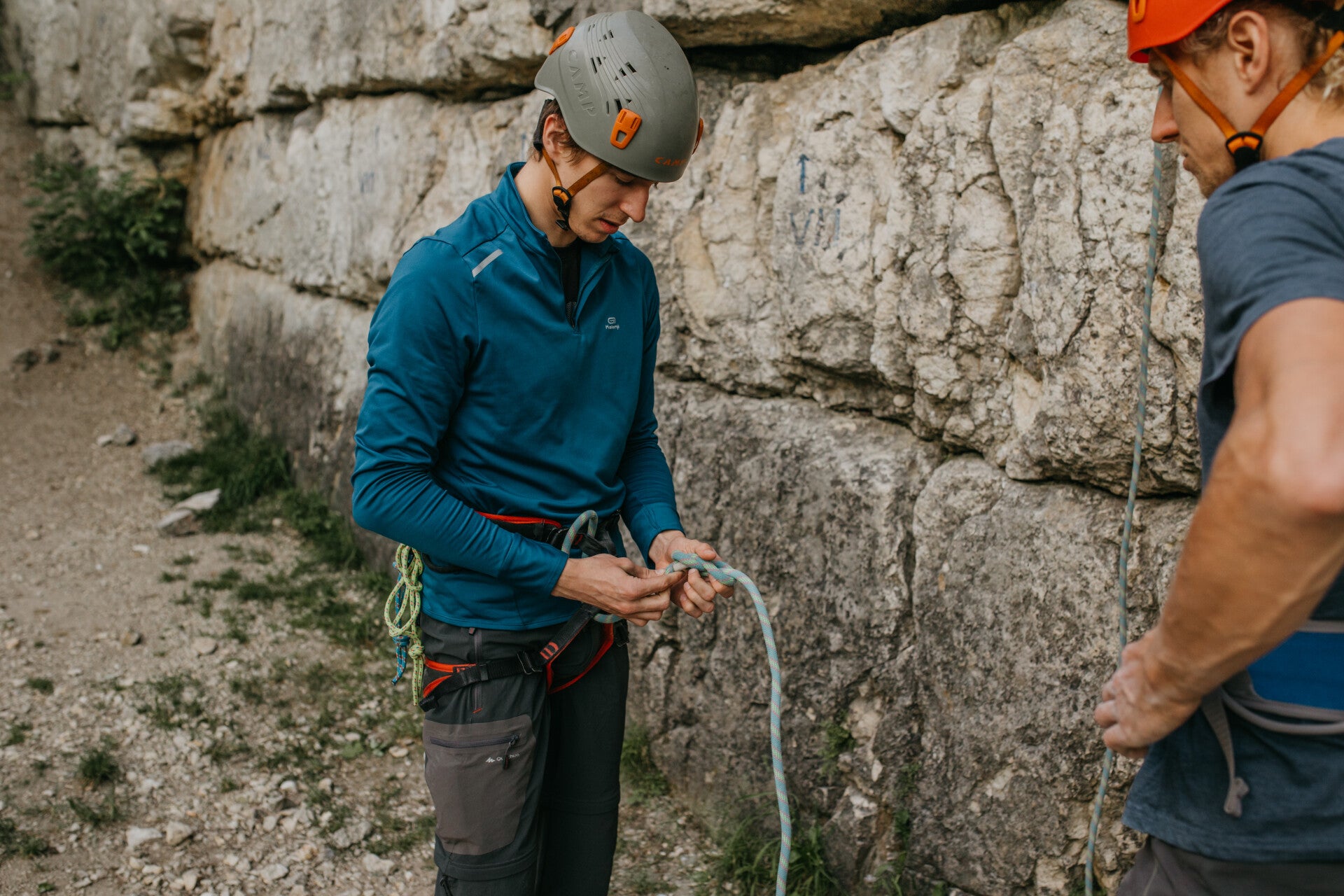 Novice climber with an rock climbing instructor learning how to tie in to a rope