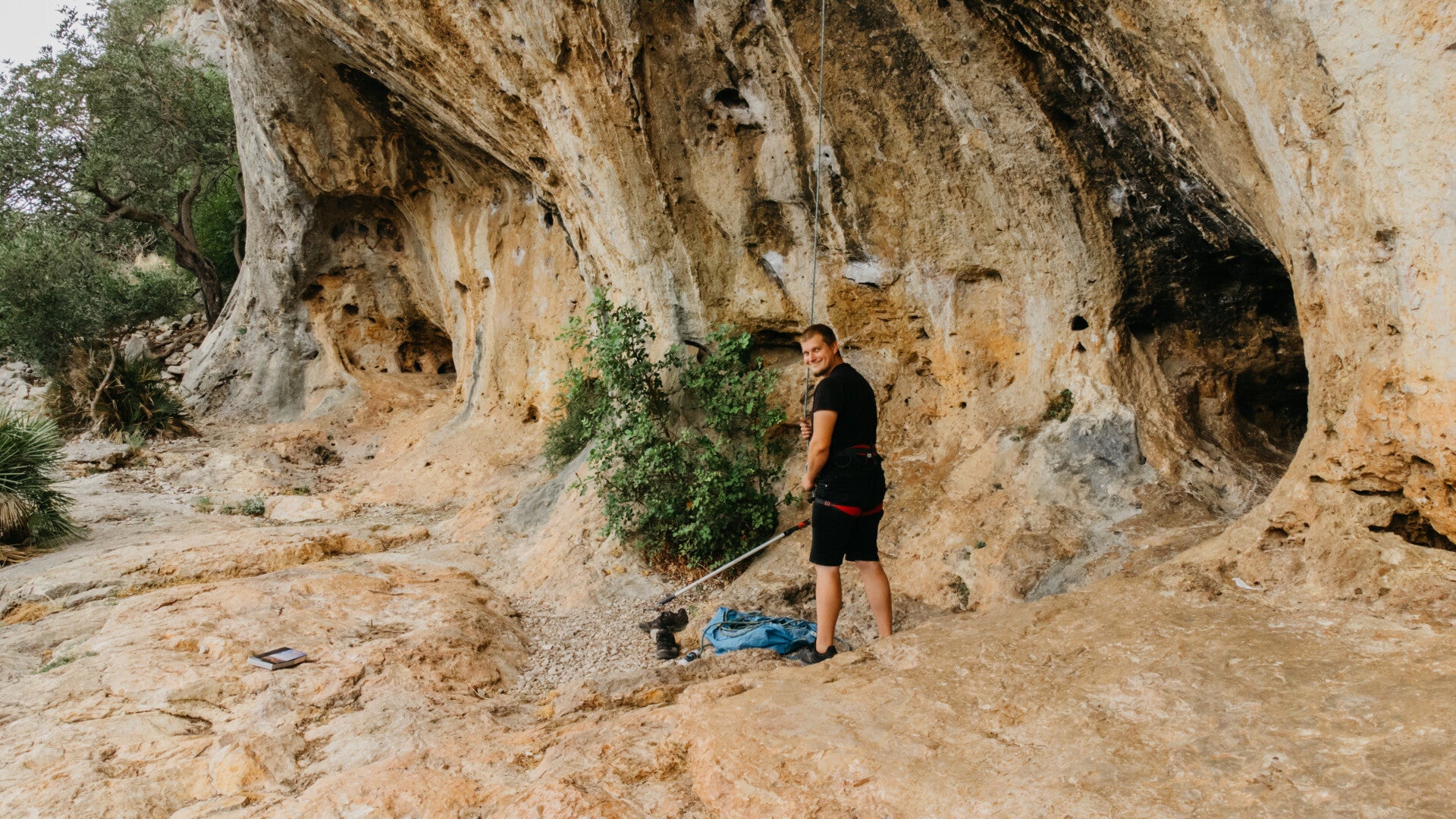 Man belaying a climber on an overhanging orange rock