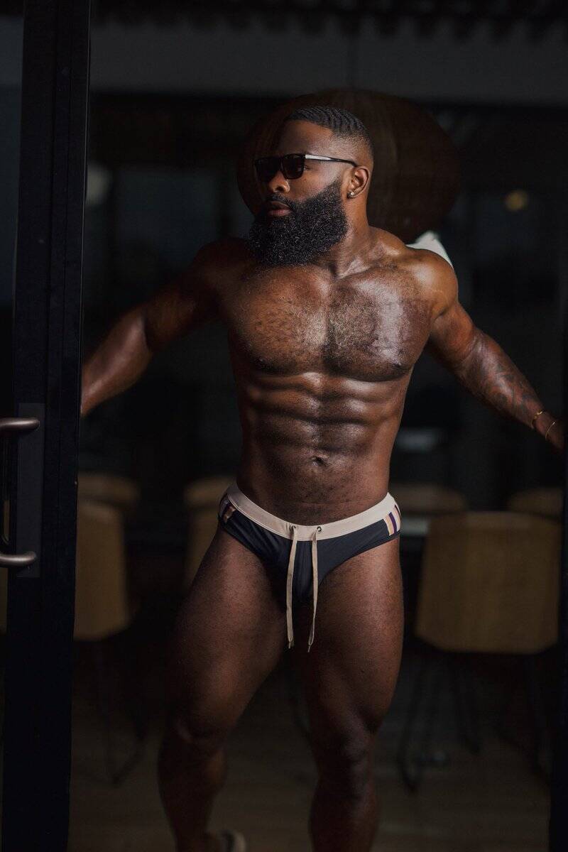 Confident fitness model showing off buff body in black shades and fitted underwear.
