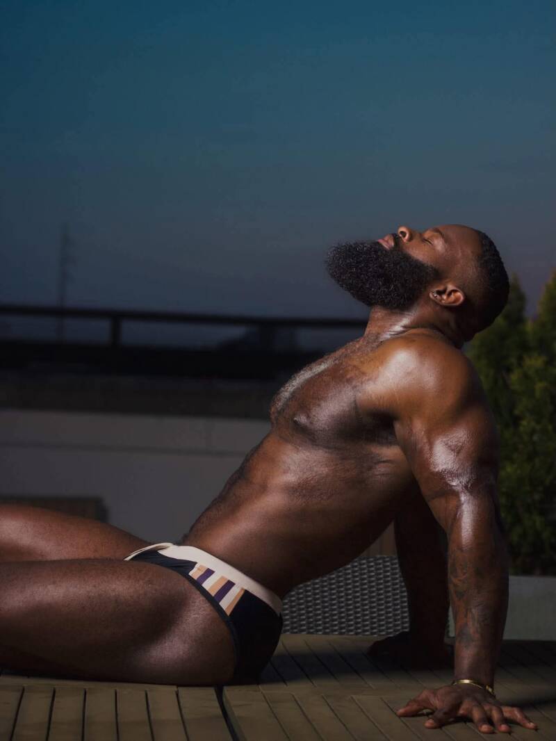 Fitness model showing off his body as he relaxes confidently outside. Style and fitness inspiration.