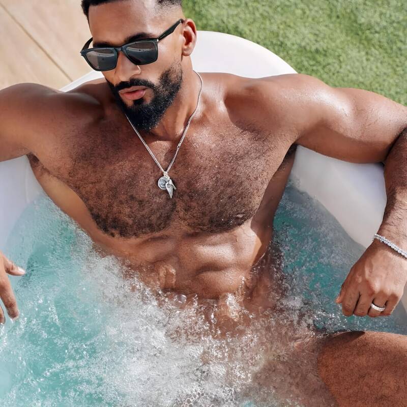 Muscular light skinned black man in swimming pool, modeling his fit body and hairy chest confidently.