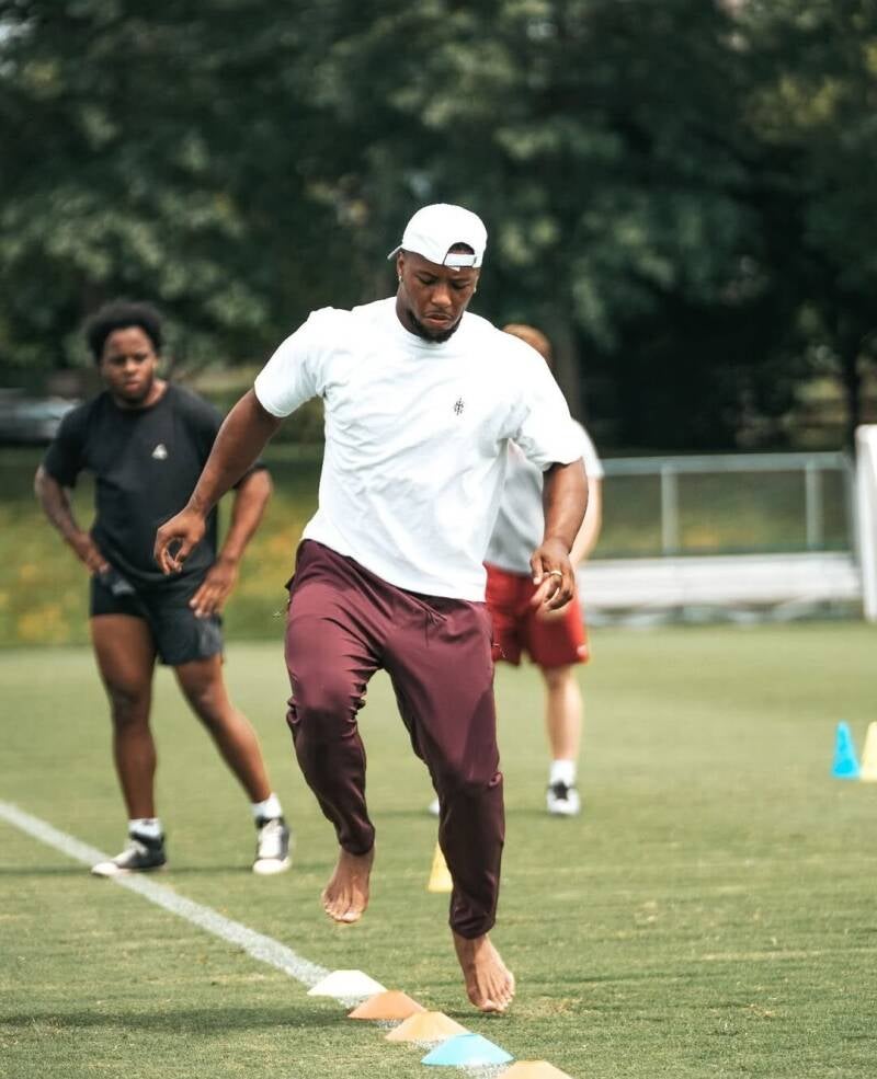 Saquon Barkley working out on football field barefoot.