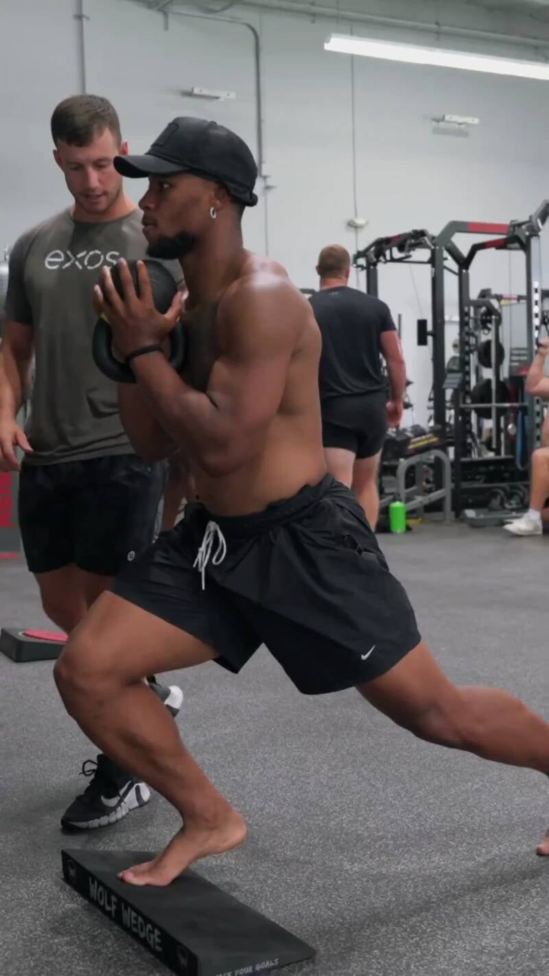 Saquon Barkley strong legs and thighs as he workout shirtless with dumbbells and his toes and top of feet close on camera.
