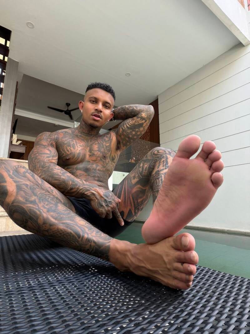 A Latin man's bare foot relaxing poolside. The skin on the sole is smooth and rough at the same time—it is healthy and relatively uniform in texture, featuring a well-defined, natural arch with deep, prominent flex lines and natural wrinkles.