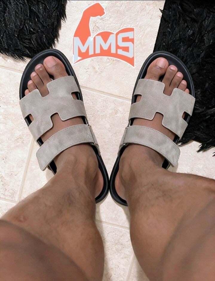 Top-down look at a Black man's attractive feet and toes in beige Hermès sandals.
