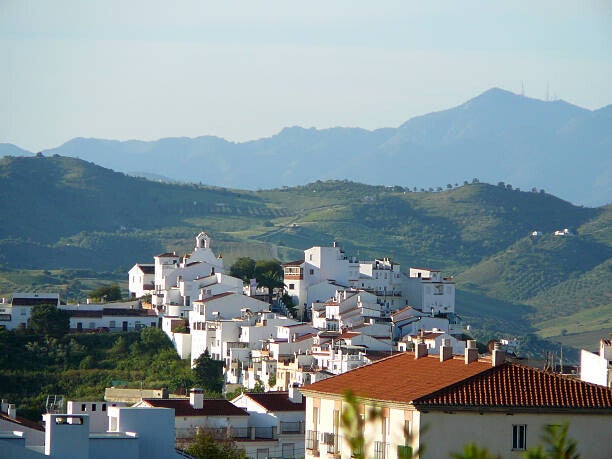 Panorámica de un pintoresco pueblo blanco andaluz con calles encaladas y tejados tradicionales bajo el cielo azul. Ilustra el Análisis Territorial Preliminar y el estudio de conectividad rural de Hogar Iberia