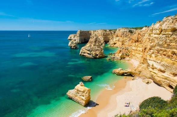 Golden limestone cliffs and offshore rock formations at Praia da Marinha in Lagoa, Algarve.