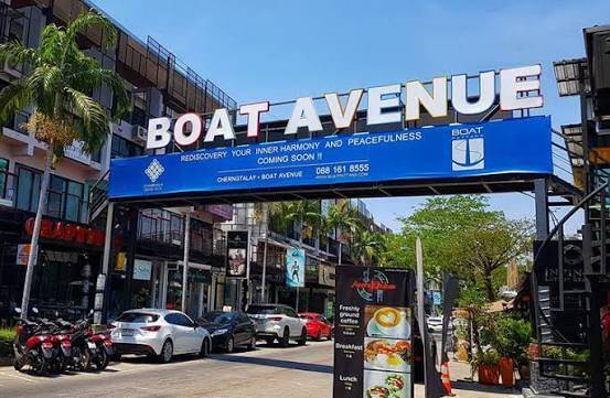 Entrance to Boat Avenue in Phuket, with shops, restaurants and parked vehicles lining the street.