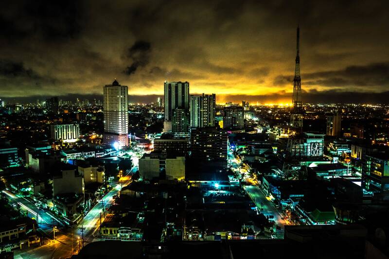 City at night: Philippine city buildings and streets glow beneath a dramatic yellow-lit night sky.