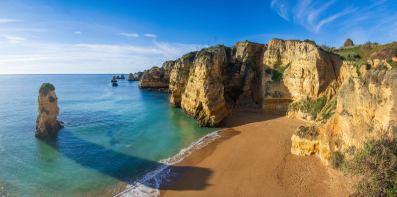 Golden cliffs and turquoise Atlantic waters along the Algarve coast near Lagos, Portugal.