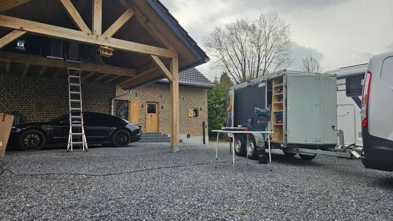 Bedrijfwagen met aanhangwagen staat bij klant om aircounit die op een hooizolderstaat te onderhouden