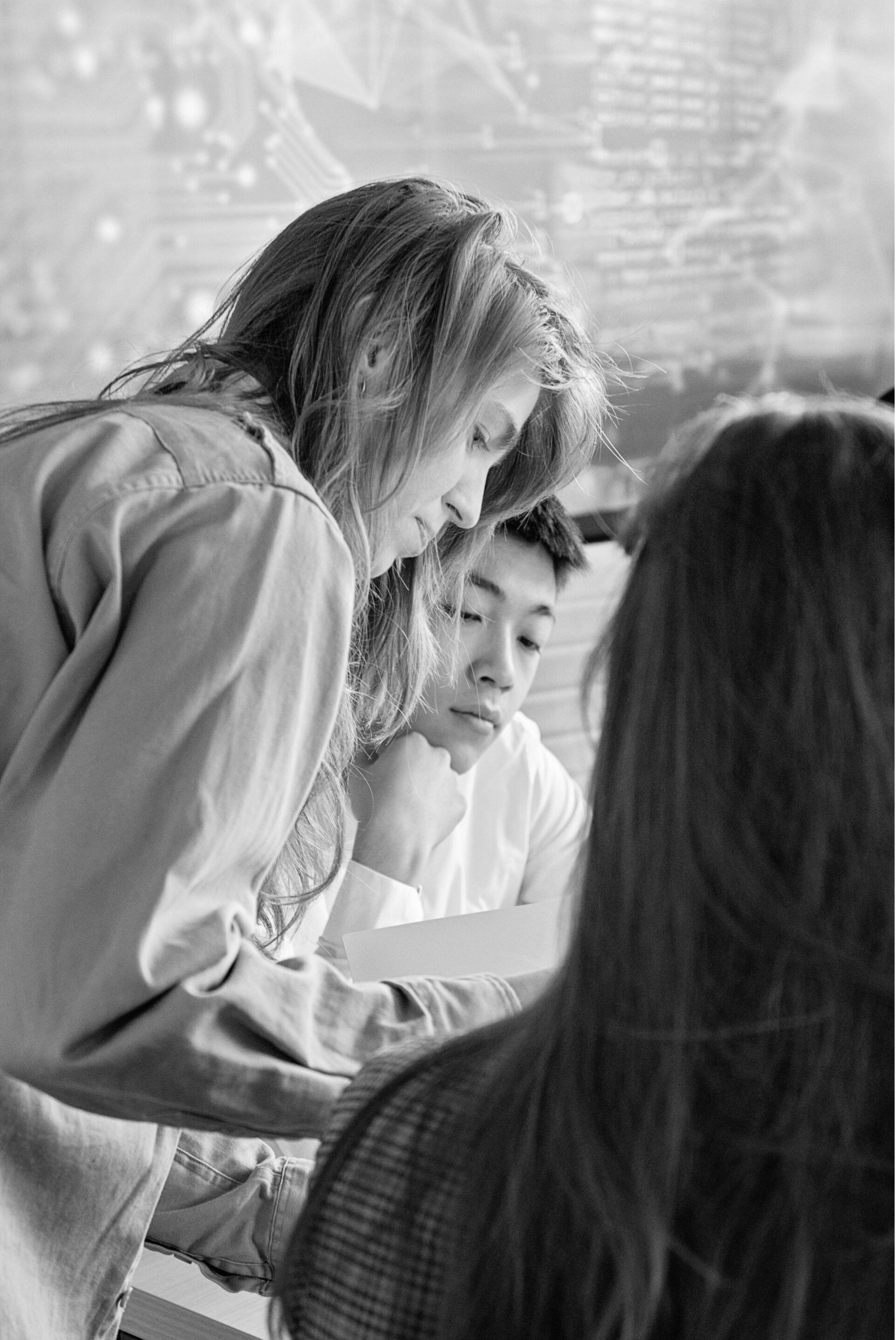 three young people clustered together discussing a paper