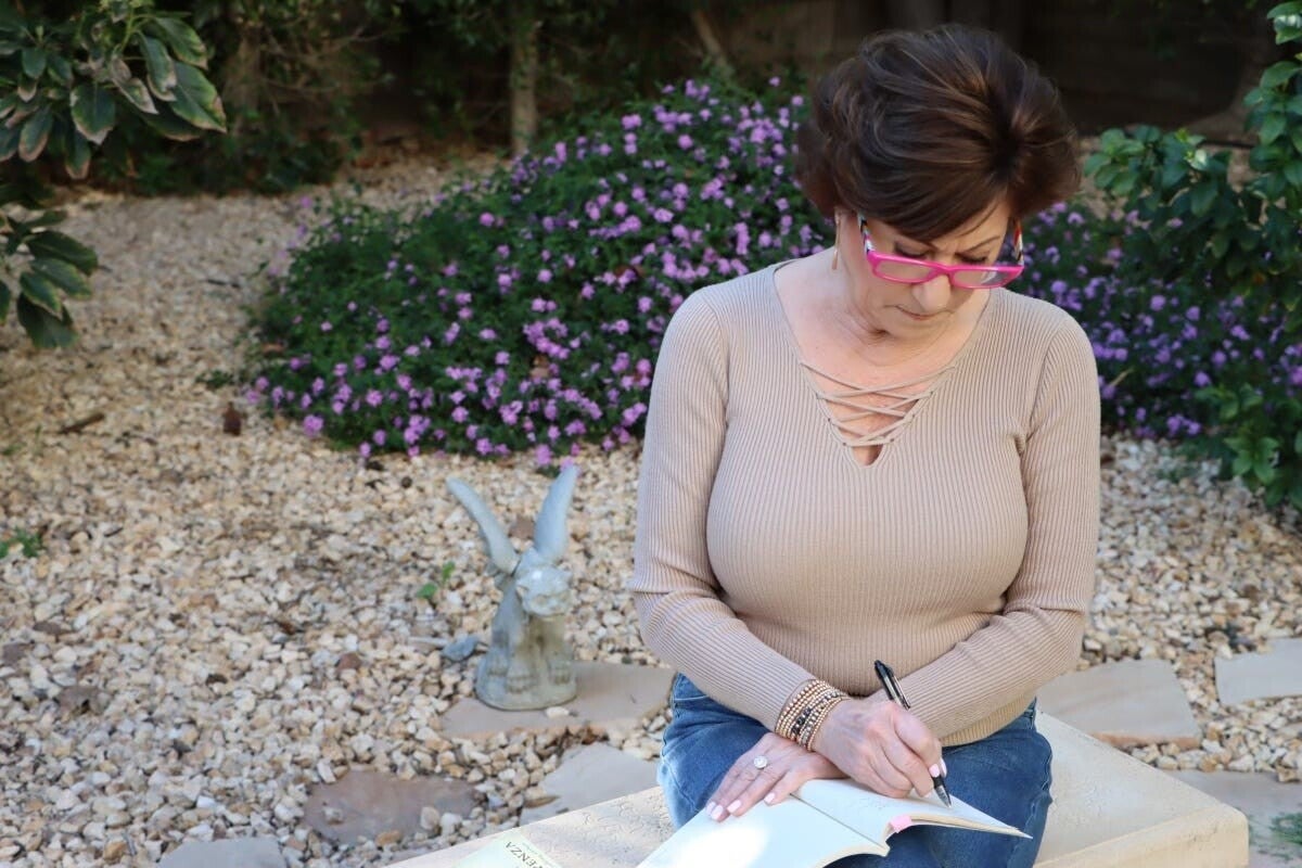 Shelley Whizin writing in a peaceful garden for her Soul Library Substack, sharing wisdom on healing and personal growth.