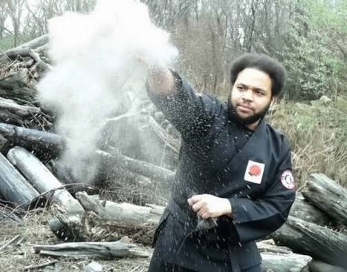 Brandon Williams, assistant instructor and third-degree black belt with the Black Scorpion Ninjutsu Society, demonstrating traditional metsubushi blinding powder techniques outdoors.
